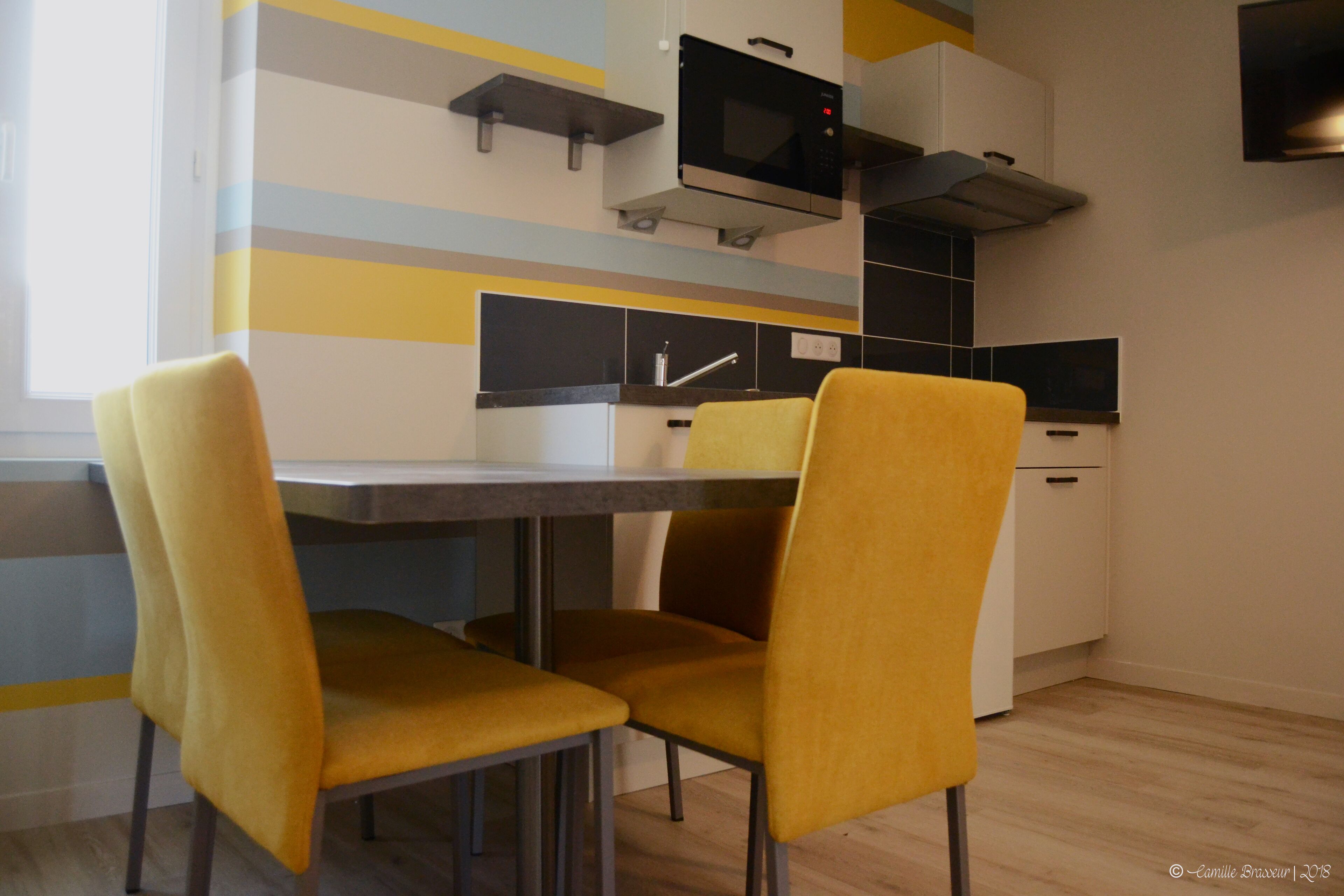 Een moderne keuken met een magnetron, fornuis en een klok aan de muur.