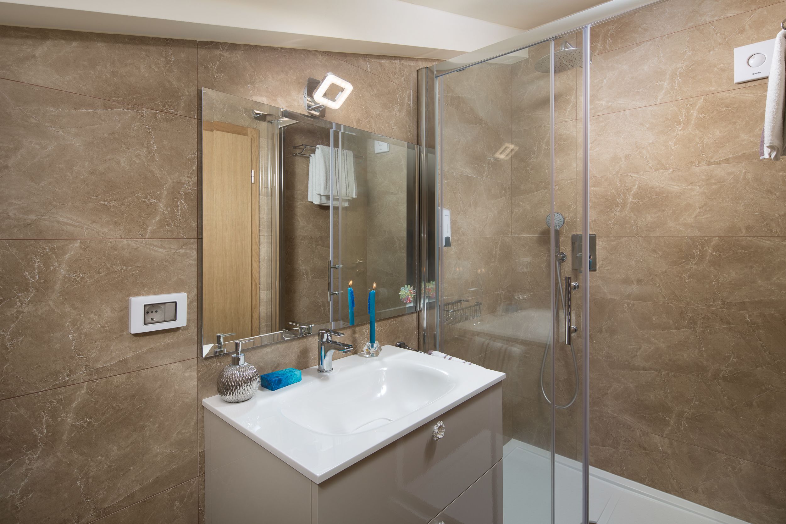 Een moderne badkamer met een glazen douchecabine, een wit wastafelmeubel en een spiegel.