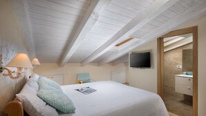 A bedroom with a large bed, a TV mounted on the wall, and a bathroom visible through an open door. - Valdibora Seaview Residence (Rovinj)