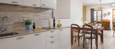 A modern kitchen with white cabinets, a built-in sink, and a dining area with wooden chairs and a table.