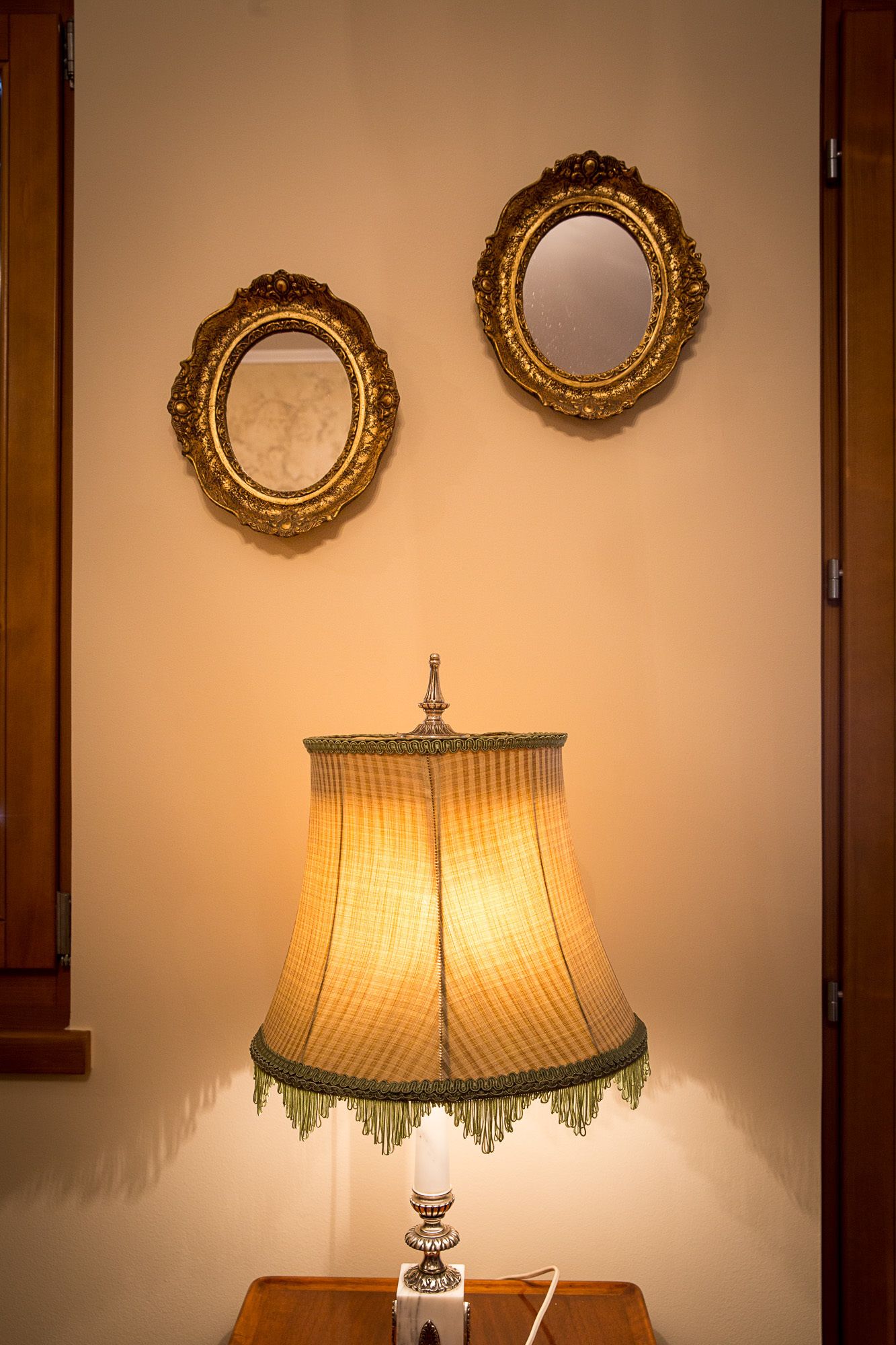 Une pièce comprenant une lampe de table, deux miroirs décoratifs et un meuble en bois.