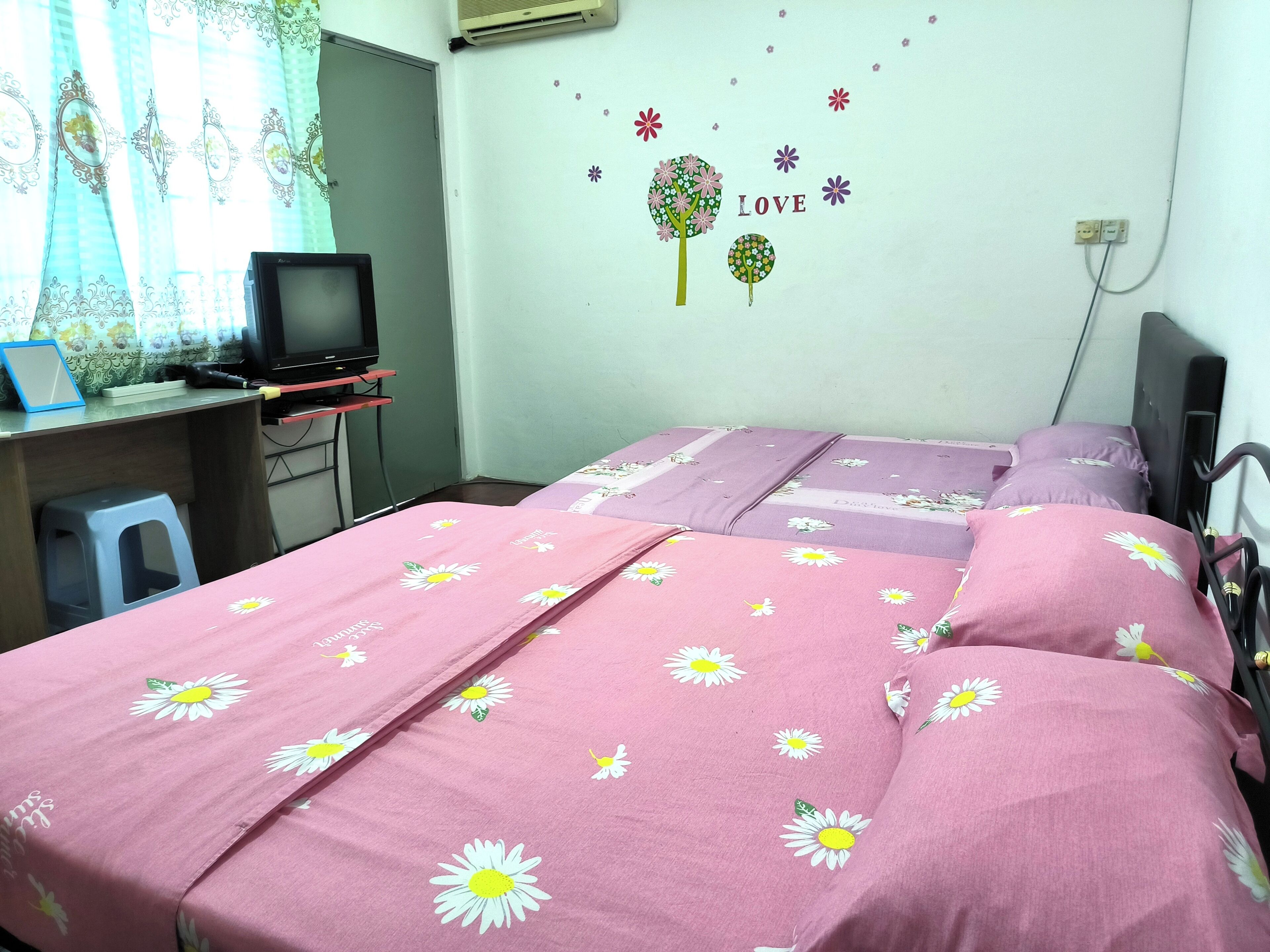 Un dormitorio con dos camas, un escritorio con una computadora y un adorno en la pared.