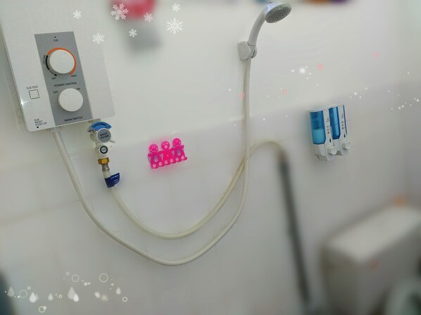 Un baño con panel de control de ducha, cabezal de ducha manual y llave de agua.