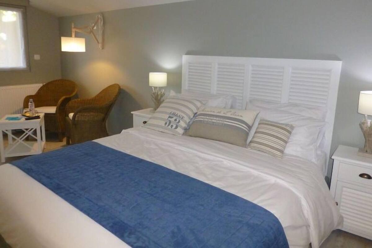 A bedroom with a large bed, two bedside tables, a chair, and a lamp.
