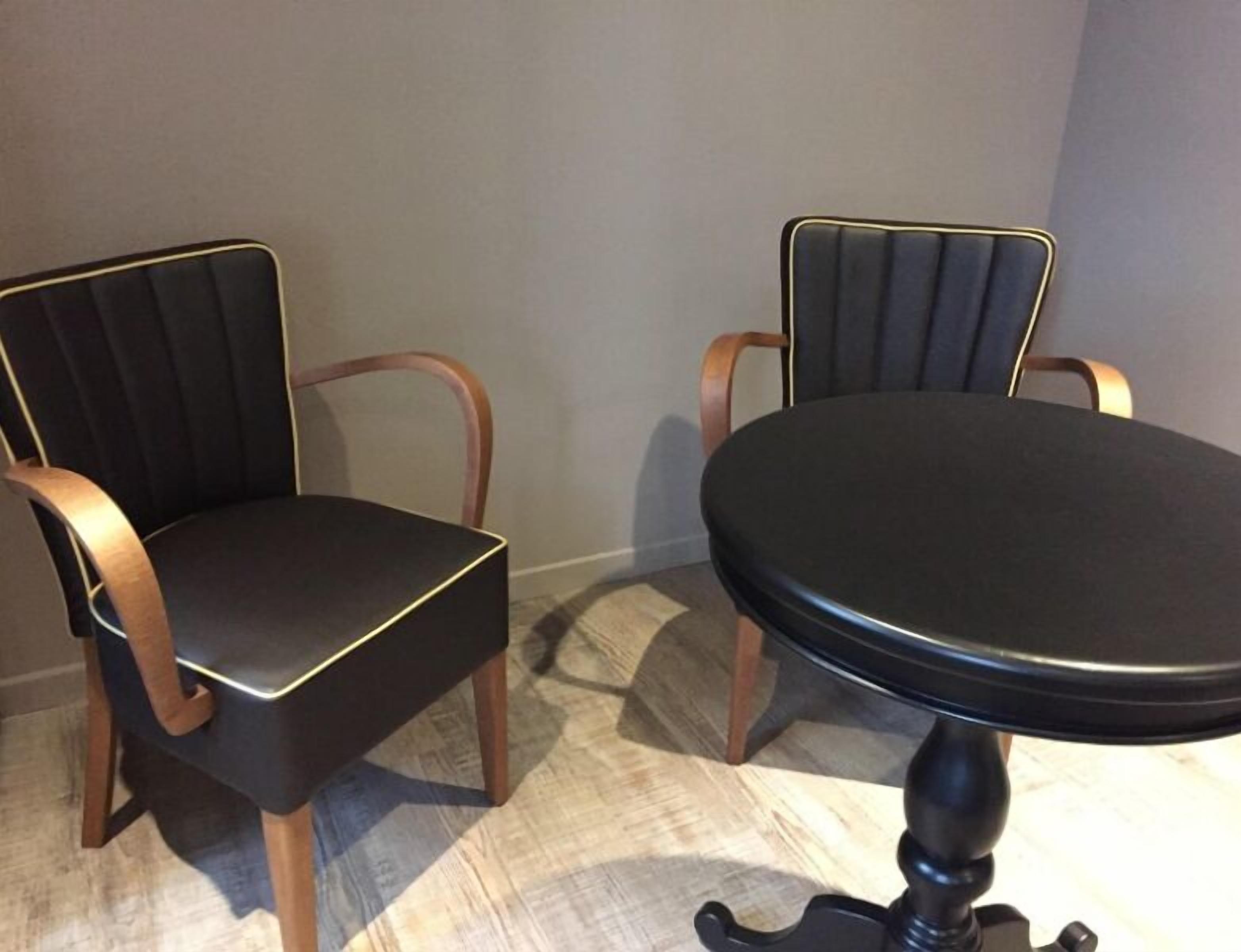 A dining area with two upholstered chairs and a round table.