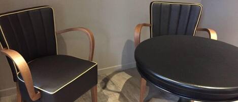 A dining area with two upholstered chairs and a round table.