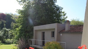 A house with a small deck and a garden with various flowers. - Le Clos Du Miroir (Courset)