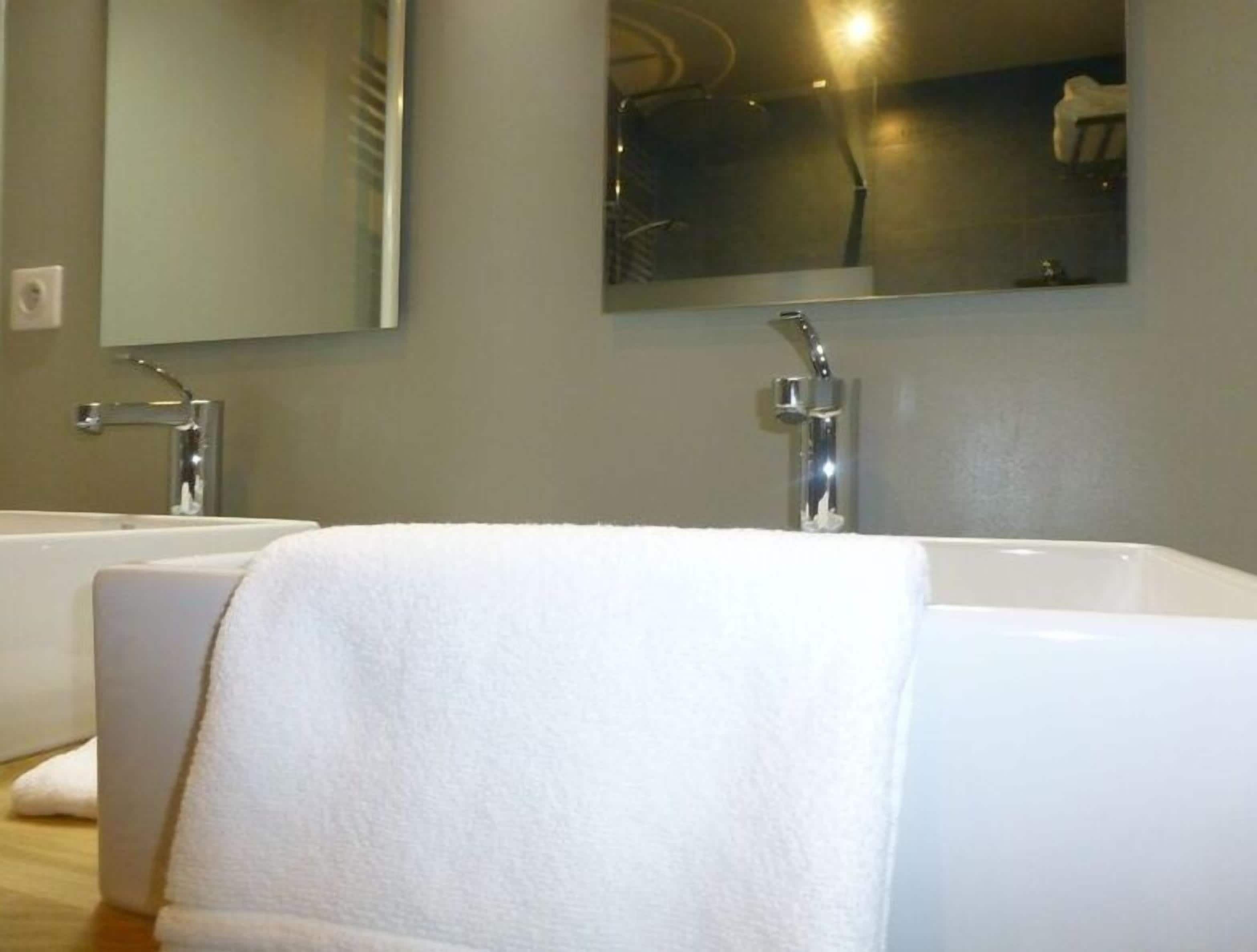 Un baño con dos lavamanos blancos y un espejo grande encima.