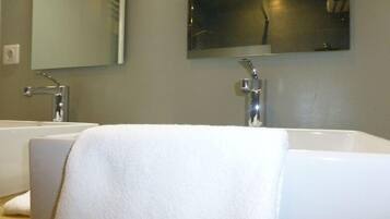 Un baño con dos lavamanos blancos y un espejo grande encima.