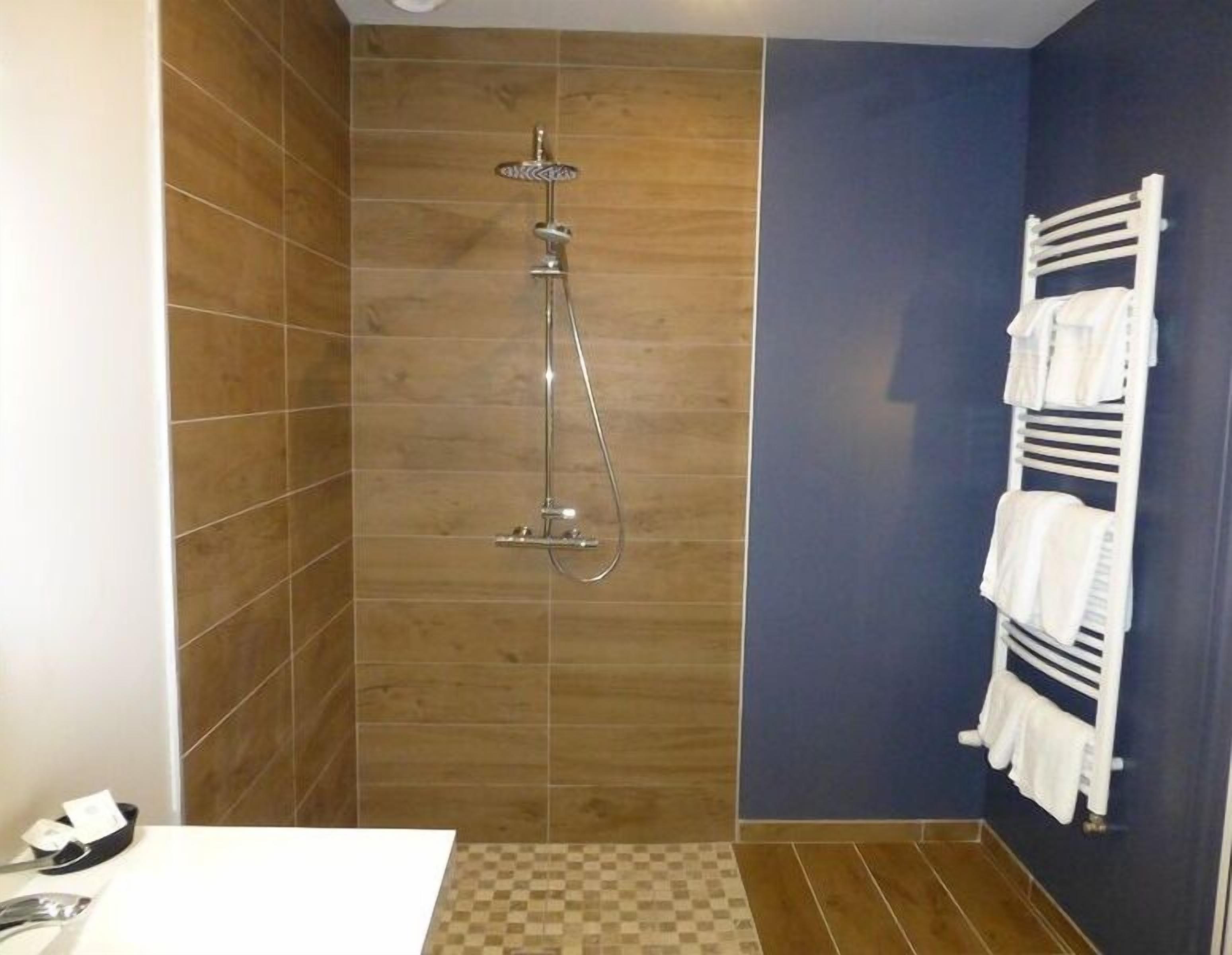 A bathroom with a shower, a towel rack, and a checkered floor.