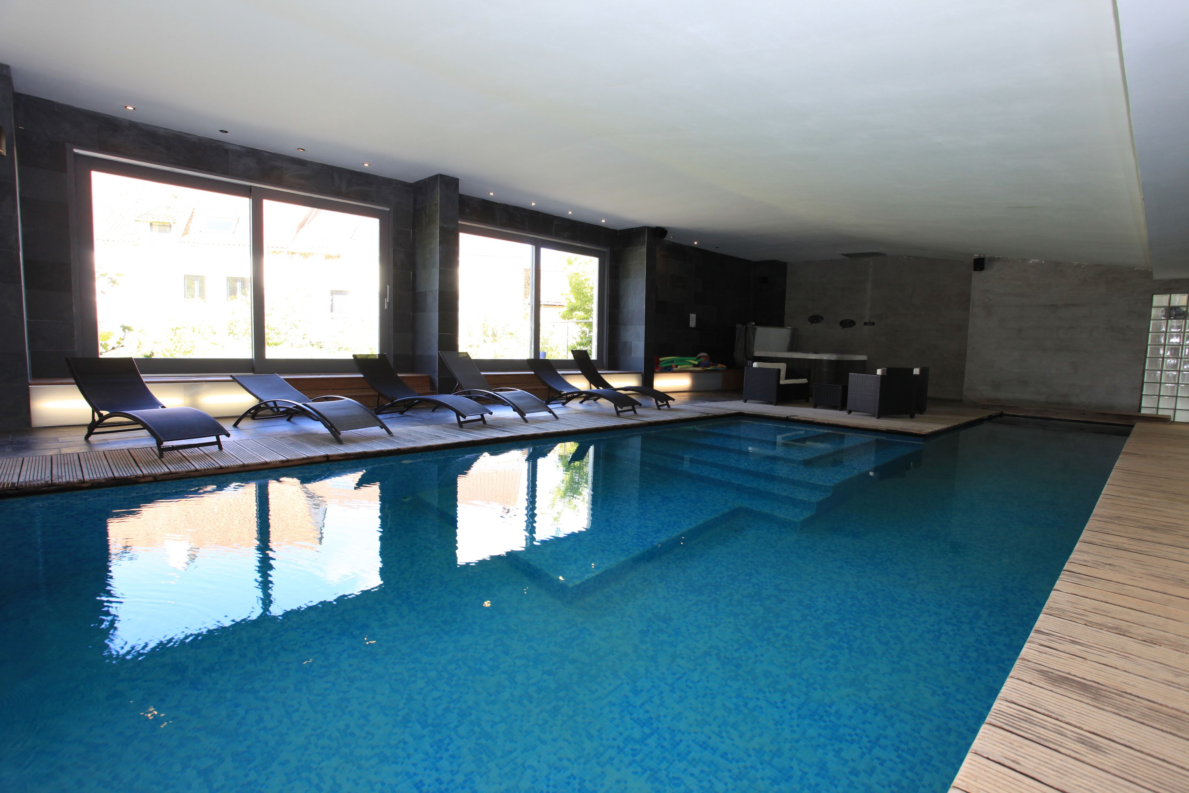Una piscina con sillas de descanso, ventanas amplias y un diseño interior moderno.