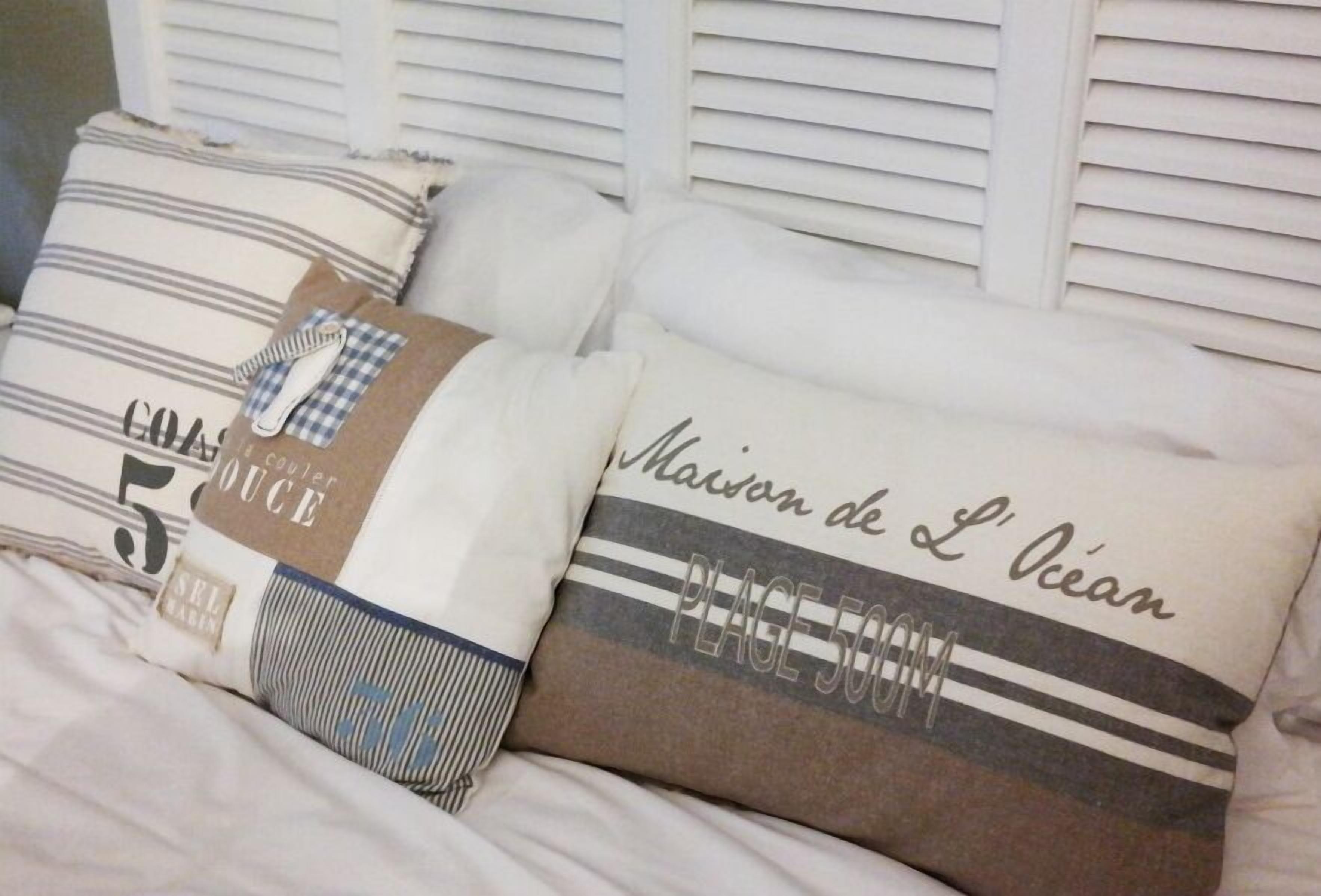 Una cama con almohadas adornadas con texto y rayas.