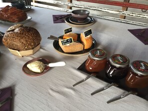 A table with various food items including sliced bread, cheese, and jars of jam.