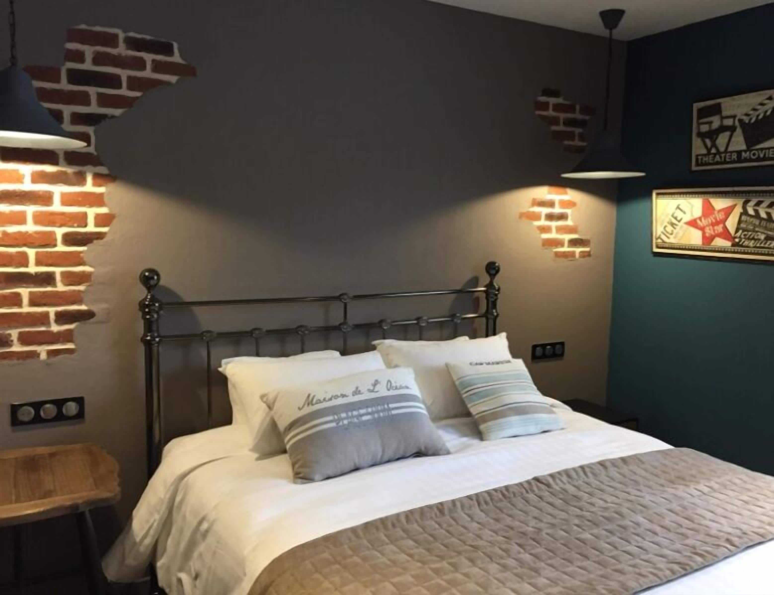 A bedroom with a brick wall, a metal bed frame, and a wall-mounted light fixture.