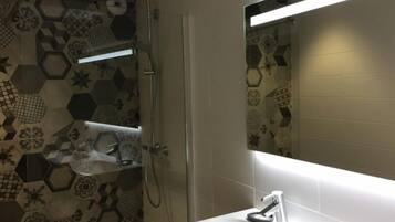 Une salle de bain avec une douche, un lavabo et un miroir.