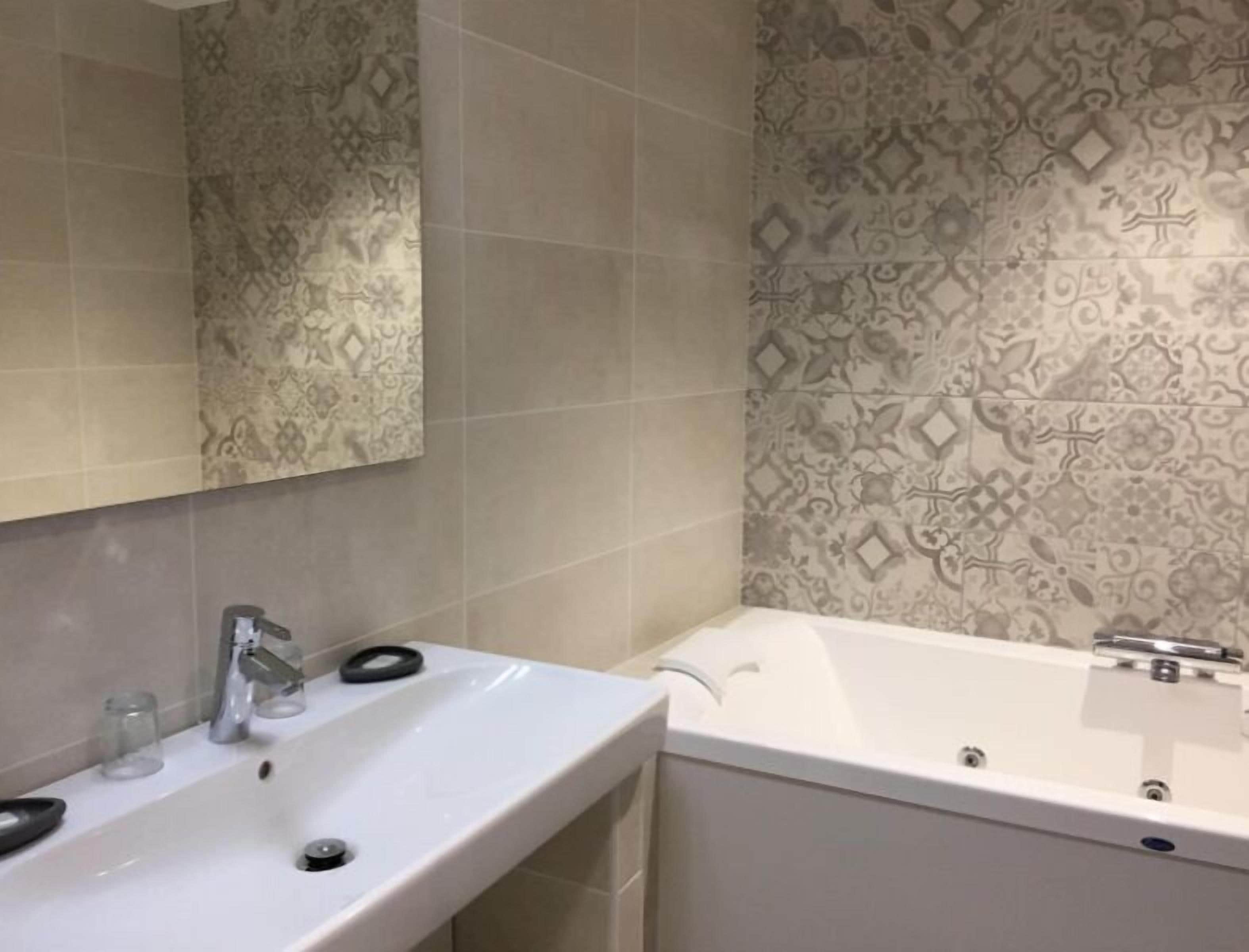 A bathroom with a white sink, a mirror, and a bathtub.