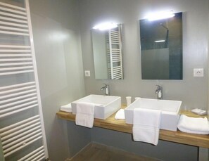 A modern bathroom with two sinks, a mirror, and a towel rack.