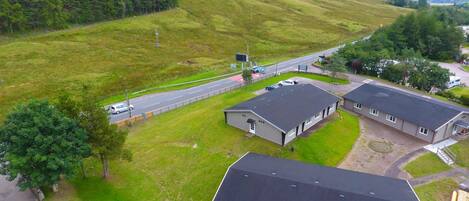 A rural setting with a road, a small building, and a parking area.