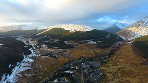 Un paisaje montañoso con un valle, un pequeño asentamiento con edificios y un río.