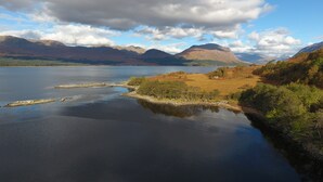 Un lago rodeado de montañas y una pequeña isla con árboles.