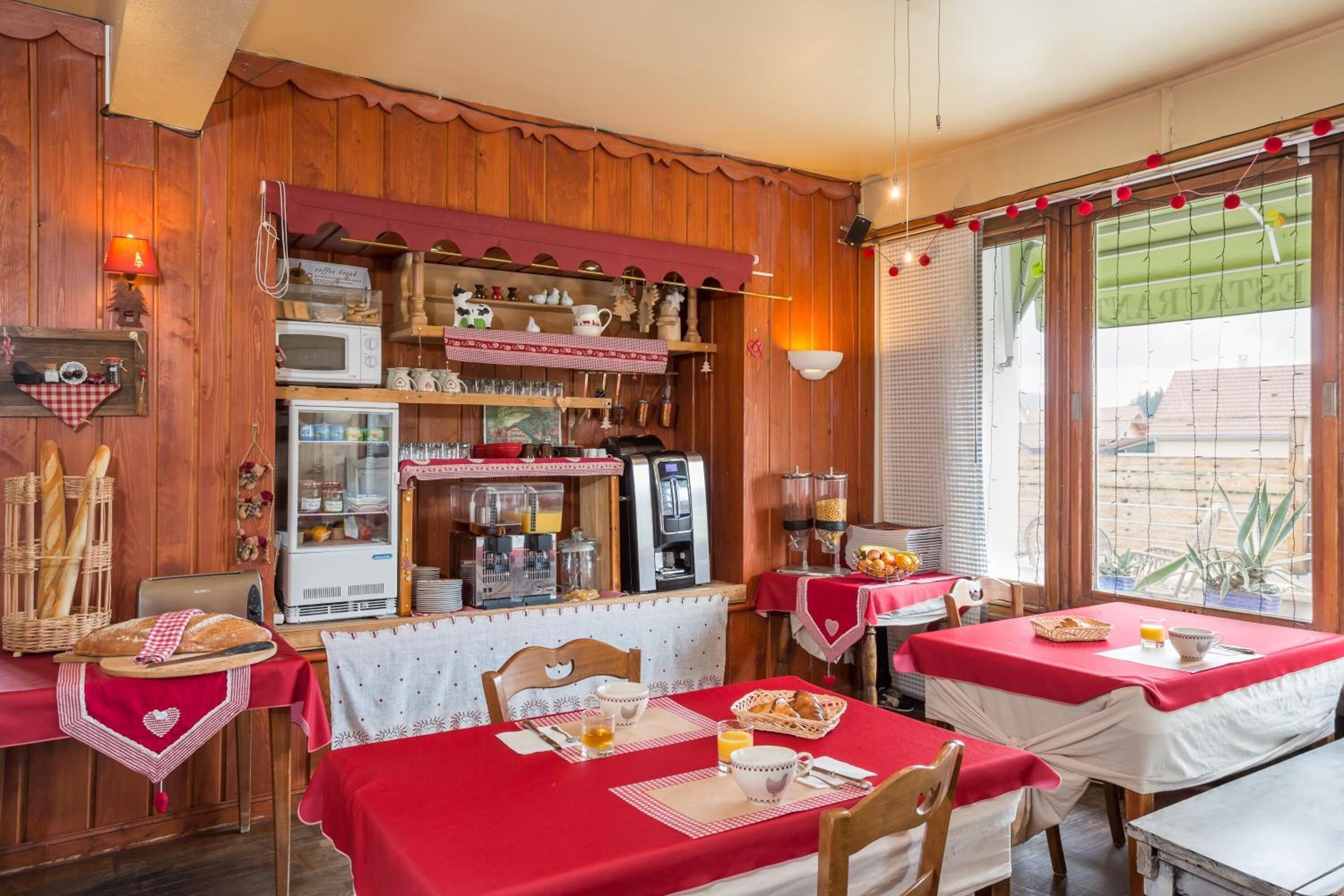 Un coin petit-déjeuner chaleureux avec des murs en bois, une machine à café et des tables préparées pour le petit-déjeuner.
