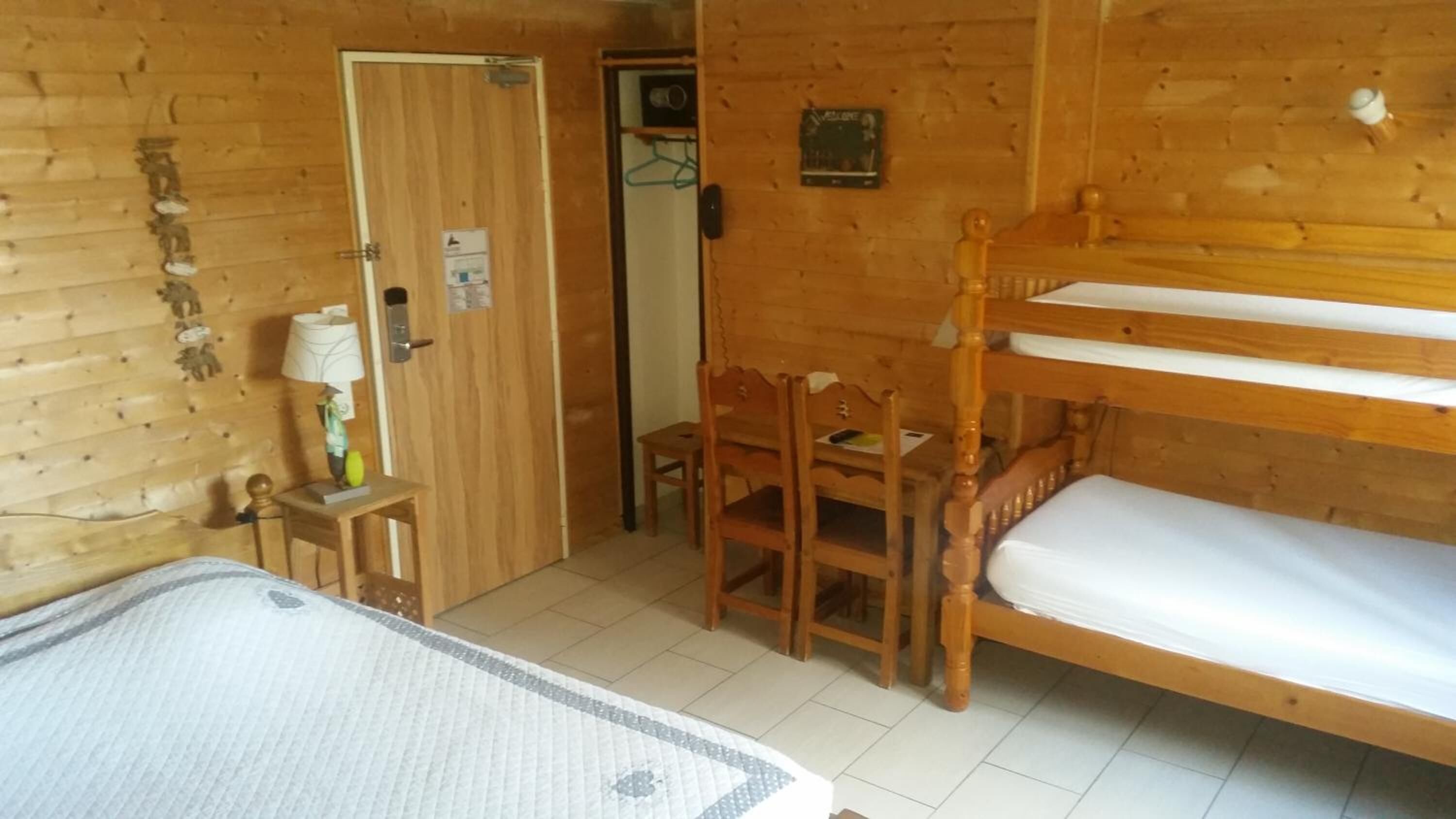Una stanza in legno con letti a castello, un tavolino e una sedia.
