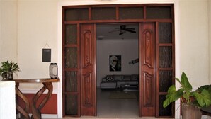 A wooden door with glass panels leading to a living room with a sofa and a ceiling fan. - Casa Estrella Mirabal (Cabarete)