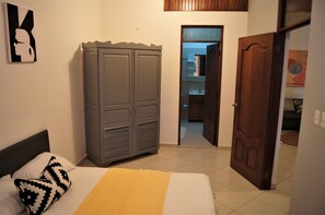 A bedroom with a bed, a wardrobe, and a door leading to a bathroom. - Casa Estrella Mirabal (Cabarete)