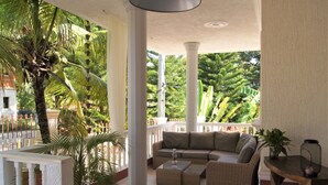 A covered outdoor seating area with a sofa, coffee table, and potted plants. - Casa Estrella Mirabal (Cabarete)