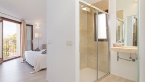 Un dormitorio moderno con una cama grande, cabina de ducha de vidrio y balcón con vistas.