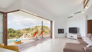 Una sala de estar moderna con un gran ventanal corredizo que da a un balcón, un televisor de pantalla plana y un sofá.