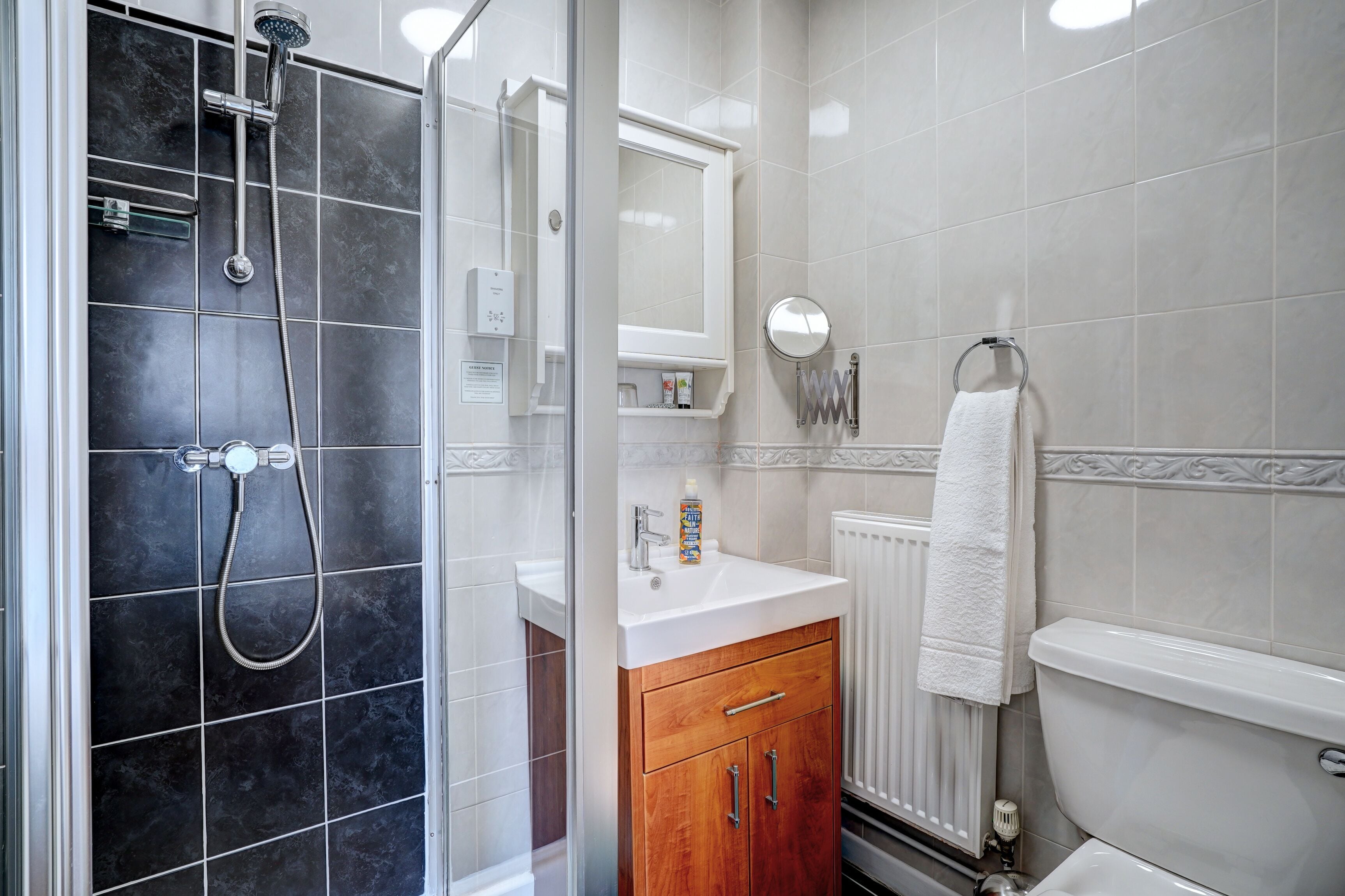 A bathroom with a shower, a sink, a toilet, and a mirror.