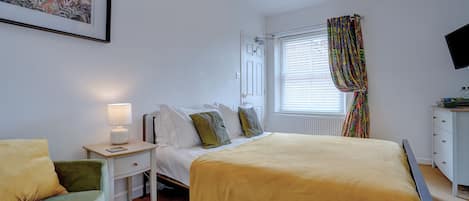 A bedroom with a bed, bedside table, lamp, and a painting on the wall.
