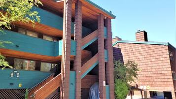 Un edificio a più piani con facciata in legno e verde, dotato di una scala e un ingresso coperto.