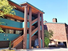 Un edificio a più piani con facciata in legno e verde, dotato di una scala e un ingresso coperto.