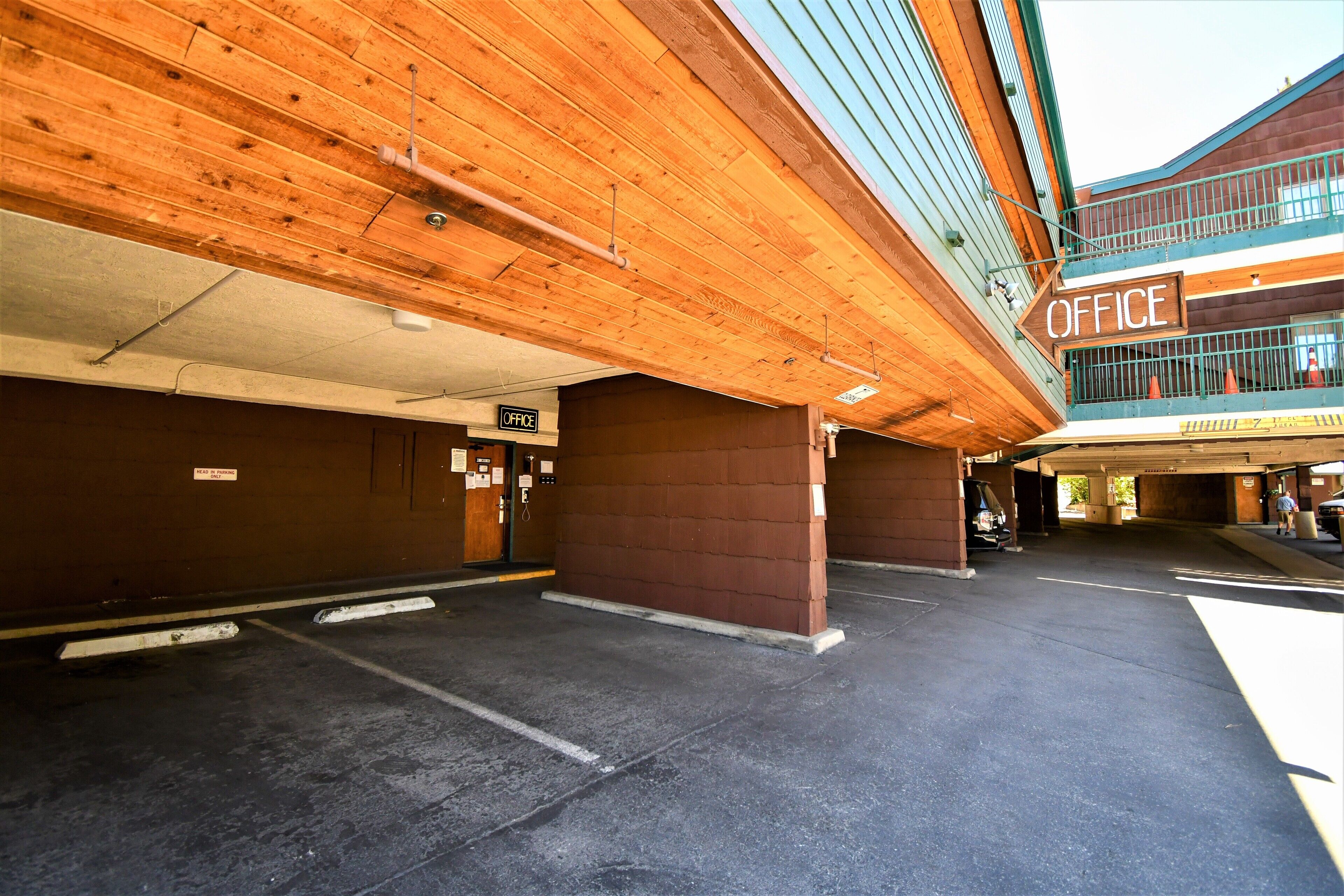 Un espace de stationnement intérieur doté d’un plafond en bois et d’un panneau indiquant la présence de bureaux.