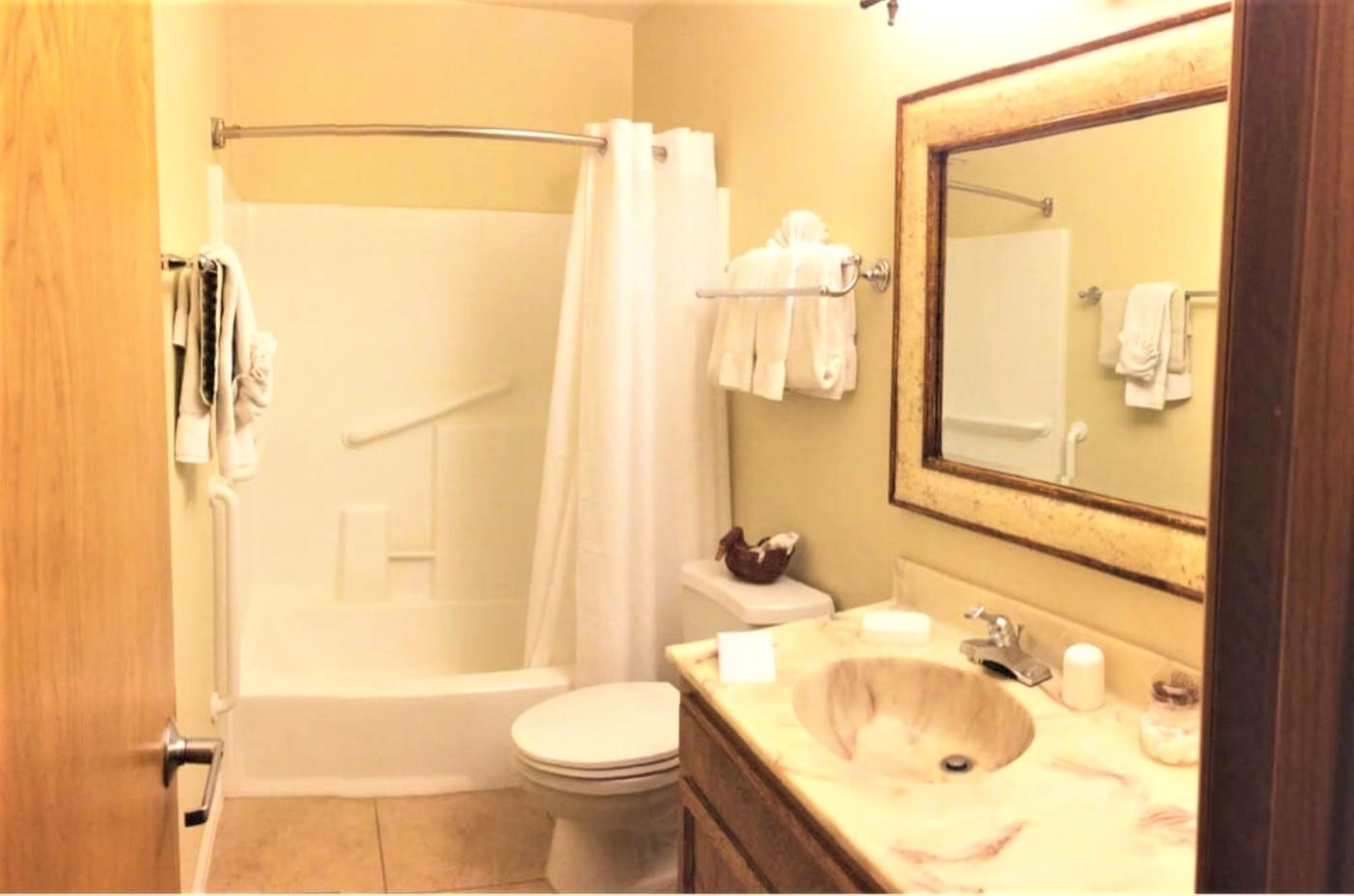 A bathroom with a bathtub, toilet, sink, and a mirror.