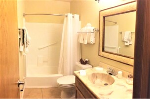 A bathroom with a bathtub, toilet, sink, and a mirror.