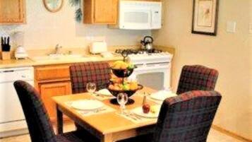 A compact kitchen with wooden cabinets, a microwave, and a dining table with plaid chairs.