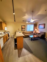 Un espacio habitable compacto con kitchenette, un sofá, una mesa de centro y un ventilador de techo.