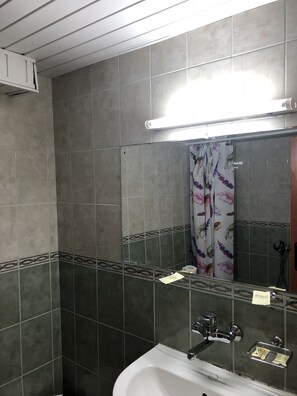 A bathroom with a white bathtub, a mirror, and a shower area with a floral curtain. - Interhotel Pomorie (Pomorie)