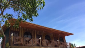 Edifici de dos pisos amb un balcó i barana metàl·lica de disseny geomètric.