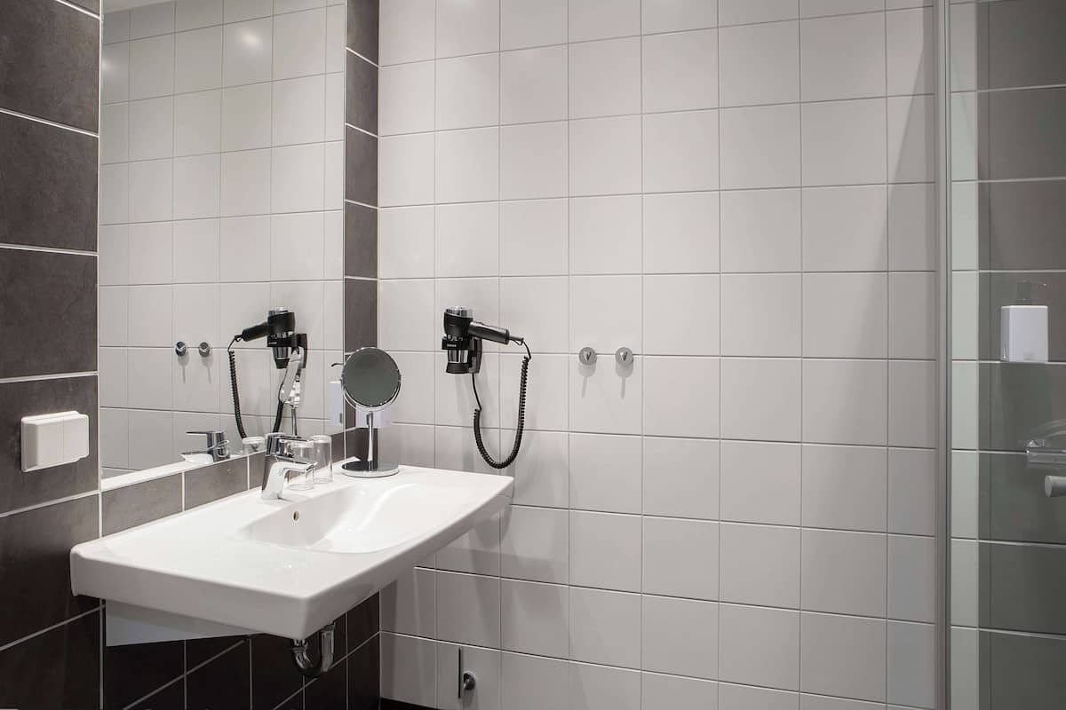 Un baño moderno con lavamanos, espejo y toallero blancos.