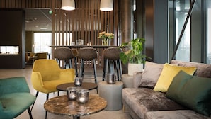 A modern lounge area with a sofa, chairs, a round table, and a bar area.