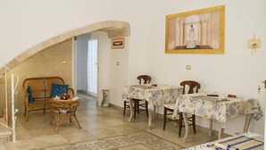 A dining area with a stone archway, wicker chairs, and tables covered with patterned tablecloths. - Le Tenute di Agnese (Alliste)