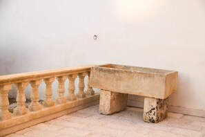 A stone bench with a balustrade on a tiled floor against a plain wall. - Le Tenute di Agnese (Alliste)