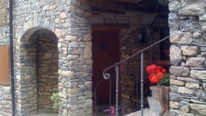 A stone building with a wooden door and a metal staircase leading to a porch. - Hotel Roch (Sort)