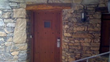Un mur de pierre avec une porte en bois, une rampe en métal et un escalier en pierre.