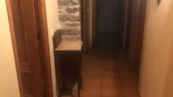 A narrow hallway with a stone wall on one side and a wooden door on the other.