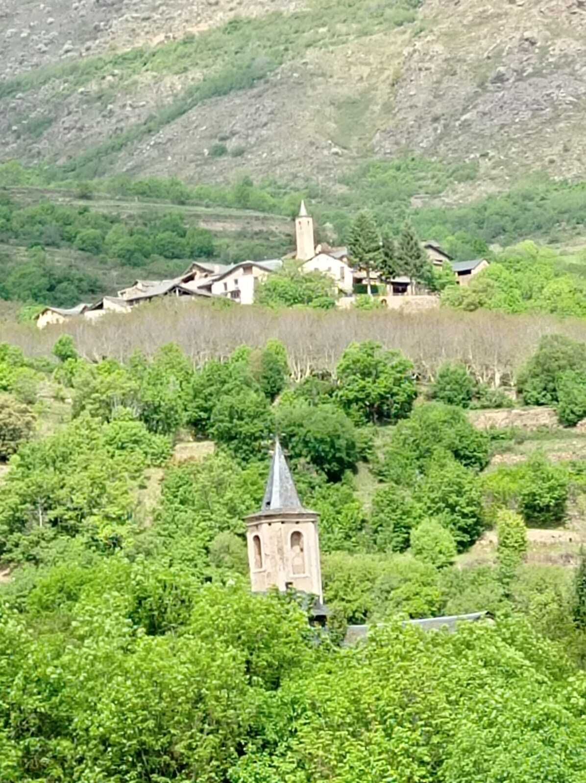 A rural village with traditional buildings, a prominent church tower, and lush greenery.